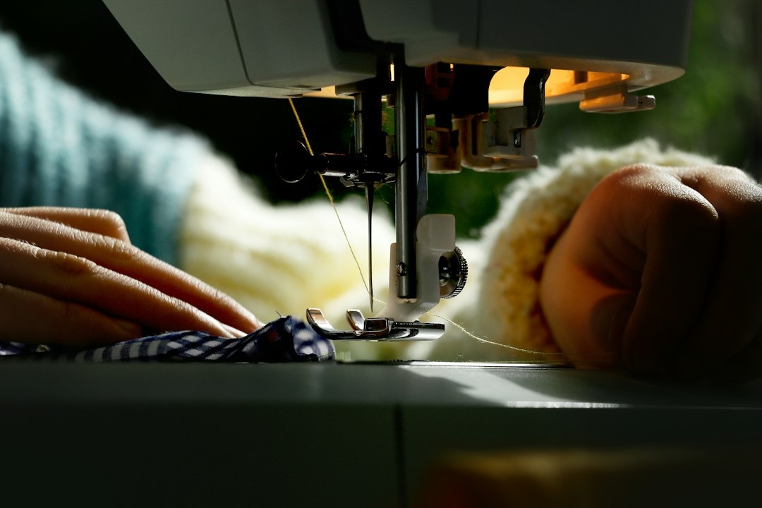 Hands guiding fabric through a sewing machine, illustrating a detailed personal story